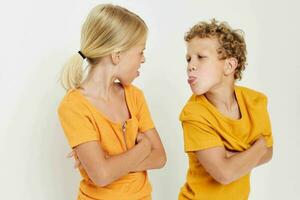 Cute stylish kids in yellow t-shirts standing side by side childhood emotions light background unaltered photo