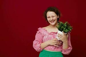 beautiful woman in green shorts flowerpot posing red background unaltered photo