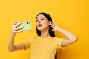 mujer con asiático apariencia en un amarillo camiseta mirando a el teléfono posando monocromo Disparo foto