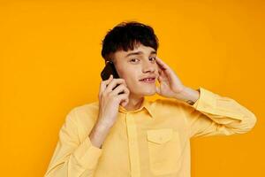 handsome man in a yellow shirt talking on the phone close-up photo