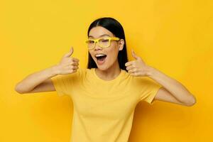 pretty brunette in glasses gesturing with hands copy-space yellow background unaltered photo