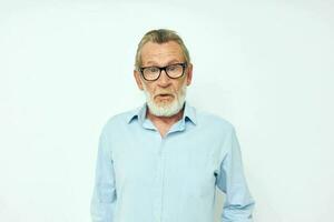 Senior grey-haired man in blue shirts gestures with his hands light background photo