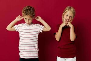 Cute stylish kids emotions stand side by side in everyday clothes red background photo