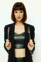 portrait of a woman in a black jacket a knife and a fork near the face isolated background photo