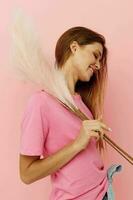 portrait of a young woman long hairstyle in pink t-shirts feathers pink background photo