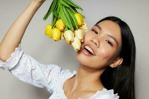 mujer con asiático apariencia con un ramo de flores de flores sonrisa de cerca estudio modelo inalterado foto