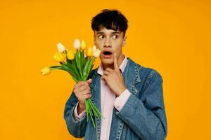 handsome man with bouquet of flowers in denim jacket fashion yellow background photo