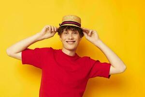 Young curly-haired man emotions red t-shirt hat studio yellow background unaltered photo