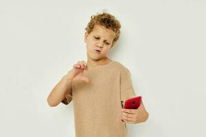 cute boy with curly hair holding a red phone light background photo
