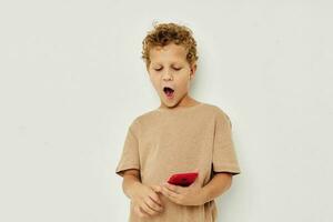 cute boy with curly hair holding a red phone light background photo