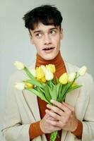 A young man in white jacket with a bouquet of yellow flowers elegant style background unaltered photo