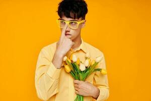 pretty man in yellow glasses with a bouquet of flowers yellow background unaltered photo