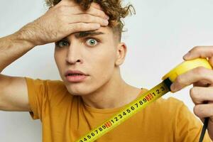 hermoso chico medición cinta medida en amarillo camiseta estilo de vida inalterado foto