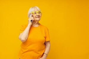 Portrait of an old friendly woman in casual t-shirt communication by phone isolated background photo