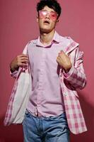 portrait of a young man in pink glasses pink blazer posing studio isolated background unaltered photo