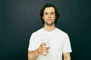 atractivo hombre en un blanco camiseta vaso de agua estilo de vida inalterado foto