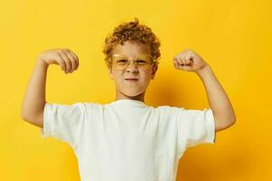 foto retrato Rizado pequeño chico en un blanco camiseta con lentes gesticulando con su manos aislado antecedentes inalterado