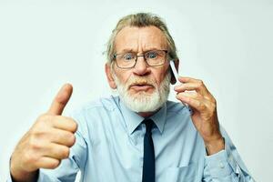 old man with phone in studio on white background shows thumb up photo