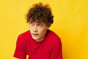 Young curly-haired man red t shirt fun posing casual wear yellow background unaltered photo