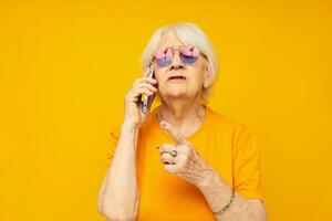 Portrait of an old friendly woman in fashionable glasses with a smartphone isolated background photo