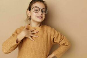 Portrait of happy smiling child girl with glasses emotions gesture hands beige background photo