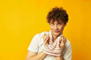 retrato de un joven Rizado hombre en un blanco camiseta sostiene un a rayas camiseta Moda juventud estilo estilo de vida inalterado foto