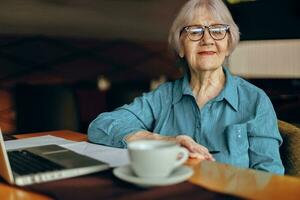 Beautiful mature senior woman working in front of laptop monitor sitting Retired woman chatting unaltered photo