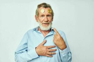 elderly man in a blue shirt bitcoins on the face isolated background photo