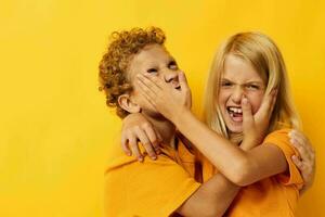 two joyful children in yellow t-shirts standing side by side childhood emotions yellow background photo