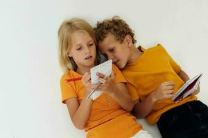 two joyful children lie on the floor with notepads and pencils childhood lifestyle unaltered photo