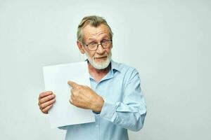 Portrait elderly man in a blue shirt and glasses a white sheet of paper unaltered photo