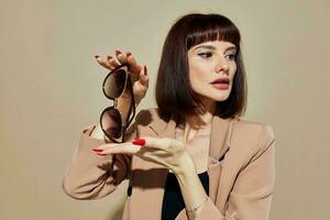 retrato de un mujer en Gafas de sol corto peludo traje gesticulando con manos ligero antecedentes foto