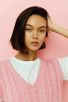 Young woman with short hair and a pink sweater pink background photo