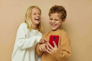 pequeño chico y niña con un rojo teléfono juntos tecnologías aislado antecedentes foto