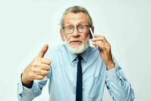 old man with phone in studio on white background shows thumb up photo