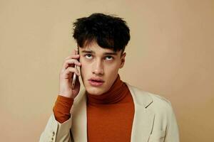 handsome guy posing with a phone in his hands in a jacket elegant style Lifestyle unaltered photo
