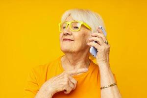 elderly woman happy lifestyle in yellow t-shirts with phone close-up emotions photo