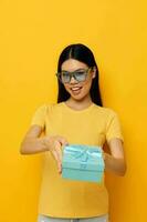 Portrait Asian beautiful young woman with a gift in glasses holiday yellow background unaltered photo