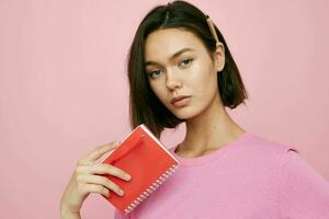 short haired brunette notepad for writing ideas pink background photo