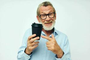 retrato de contento mayor hombre gestos con su manos un vaso de bebida aislado antecedentes foto