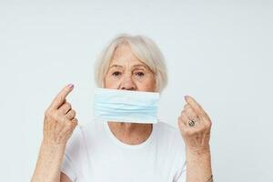 emotional elderly woman medical mask in hand safety isolated background photo