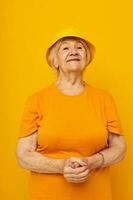 Photo of retired old lady in yellow t-shirts hat posing cropped view