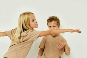 retrato de linda niños en beige camisetas posando para divertido aislado antecedentes foto