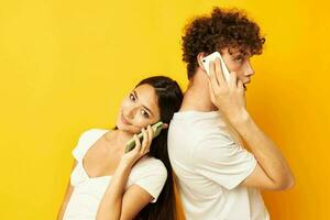 a guy and a girl stand with their backs to each other talking on the phone photo