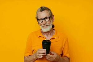 Senior grey-haired man in a yellow T-shirt a glass with a drink unaltered photo