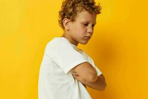 Cheerful boy in white t-shirt posing studio yellow background photo