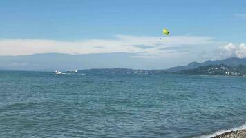 batumi, Georgia -25 julio, 2022 - Pareja parasailing con amarillo sonriente paracaídas en vacaciones en batumi playa recurso en verano fiesta vacaciones con ciudad puntos de referencia famoso batumi video