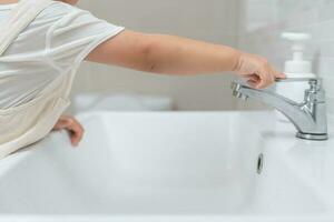 Little kid's hand closed the faucet at sink in house with mom. Mother teaches child to save water. keeps turning off the water to save world energy and protect the environment, world water day photo