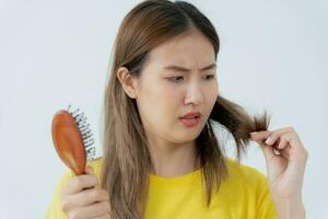 asiático mujer muy triste y trastornado mirando a dañado cabello, pelo pérdida, pelo adelgazamiento problema, vitamina deficiencia, calvicie, posparto, biotina, zinc, menstrual o endocrino trastornos, hormonal desequilibrio foto