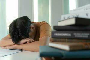 el estudiante asiático tiene ansiedad debido a los exámenes, los hombres se preparan para el examen y aprenden lecciones en la biblioteca. estrés, desesperación, prisa, malentendido lectura, desanimado, expectativa, conocimiento, cansado foto